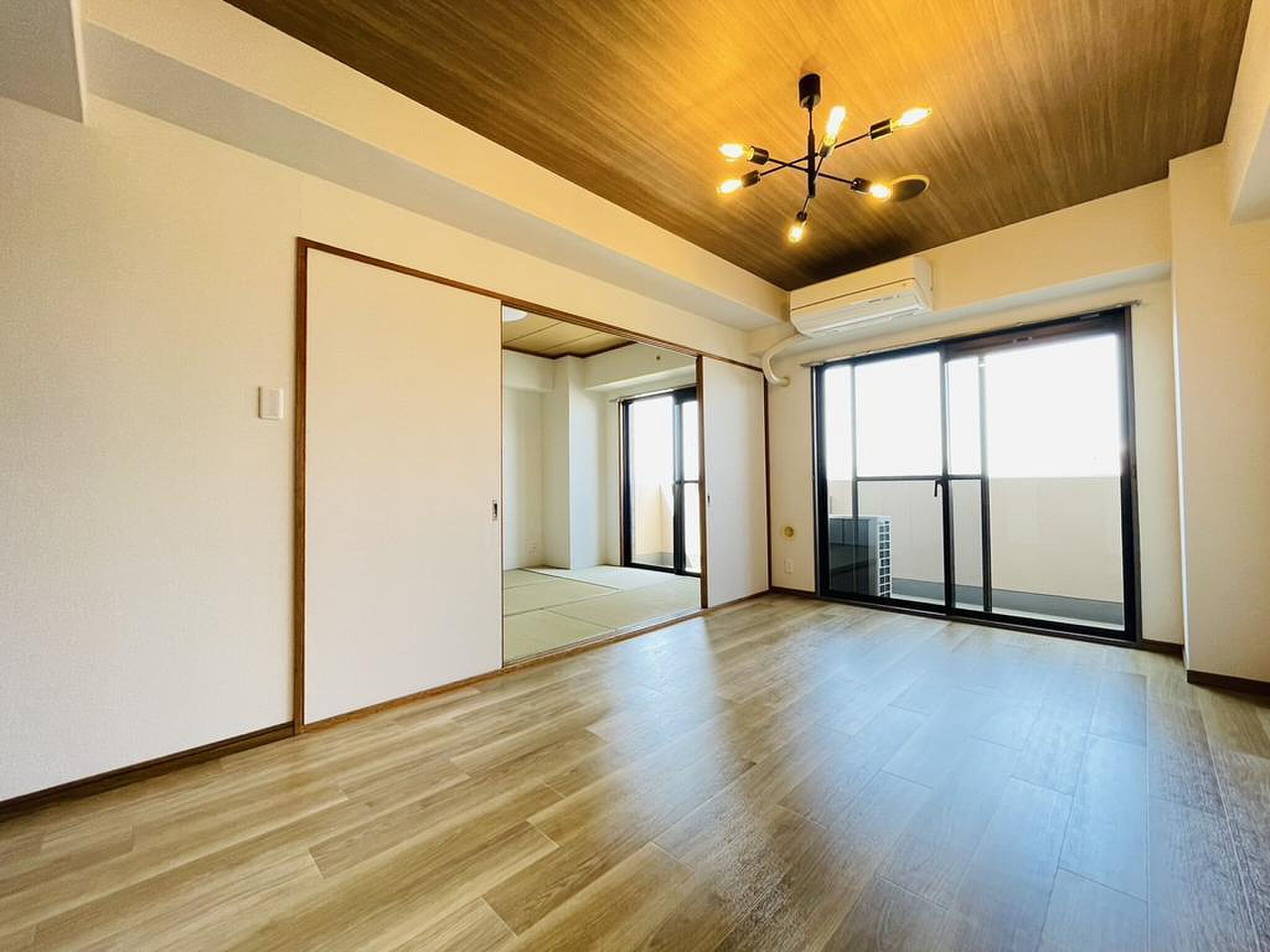 最上階、掃き出し窓の先に広がるバルコニーと木目天井のリビング
